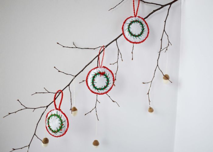 Baumzweig mit selbstgebastelten Ornamenten und Eicheln geschmückt
