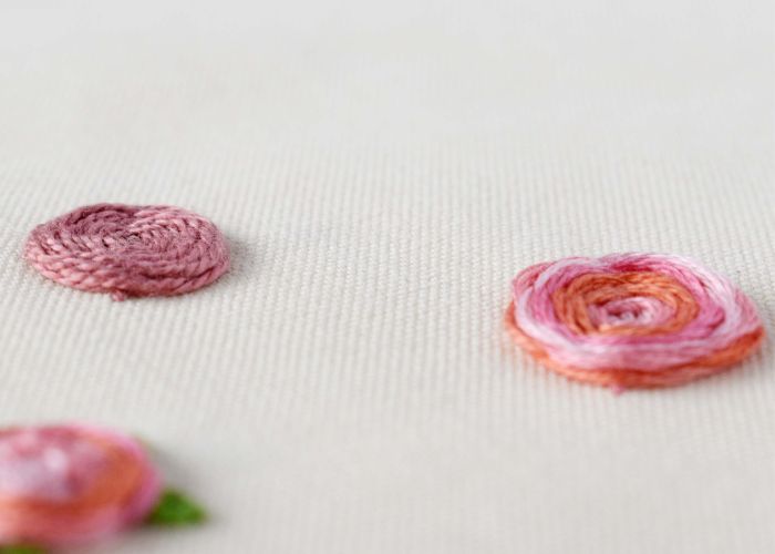 Rosa Blumen handgestickt mit gewebtem Radstich auf weißem Stoff