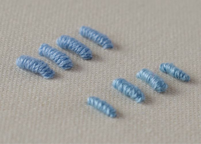 Das Mustertuch des Bullion-Knotenstichs. Stickerei mit blauem Stickgarn und Perlenbaumwolle